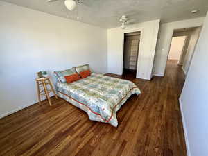 Bedroom featuring dark wood-style floors, a textured ceiling, ceiling fan, and a closet