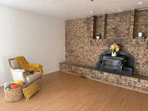 Sitting room featuring a wood stove, wood finished floors, and a textured ceiling