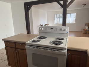Kitchen featuring electric range, light countertops, dark wood finish cabinetry, and open floor plan
