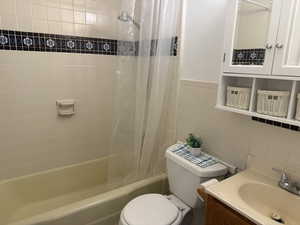 Full bath with tile walls, vanity, and shower / bath combination with curtain