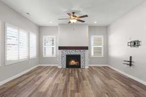 Unfurnished living room featuring dark wood-style flooring, a tile fireplace, a ceiling fan, and recessed lighting