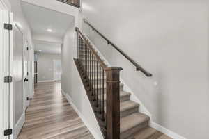 Stairway with wood finished floors and recessed lighting