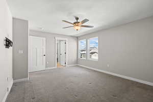 Unfurnished bedroom with ceiling fan, a textured ceiling, and carpet
