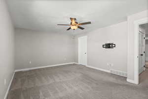 Carpeted empty room with a ceiling fan and baseboards