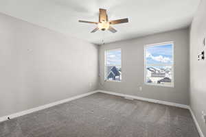Carpeted empty room featuring baseboards and a ceiling fan
