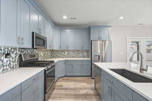 Kitchen featuring stainless steel appliances, light stone countertops, gray cabinetry, recessed lighting, and light wood-style floors