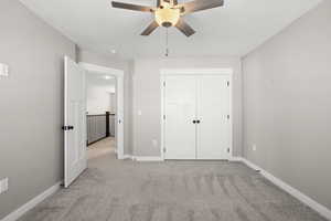 Unfurnished bedroom featuring light carpet, a closet, and ceiling fan