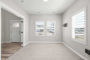 Foyer entrance with light colored carpet and baseboards