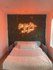 Bedroom featuring an accent wall and wood finished floors