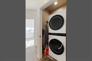 Laundry area with light carpet and stacked washing machine and dryer