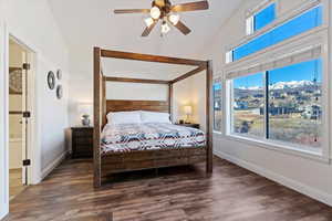 Bedroom featuring a mountain view, dark wood-type flooring, lofted ceiling, ceiling fan, and ensuite bath