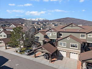 View of front facade with a mountain view, a residential view, stone siding, and a garage