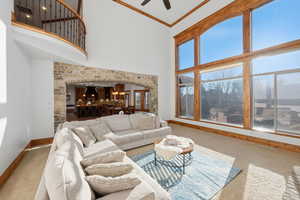 Living area with crown molding, arched walkways, a high ceiling, carpet, and ceiling fan