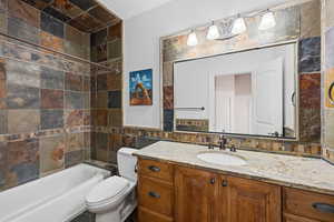 Full bath with vanity, tile walls, and bathing tub / shower combination