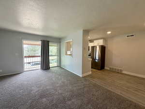 Carpeted empty room with a textured ceiling and baseboards