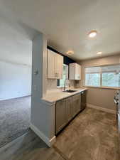 Kitchen with a textured ceiling, backsplash, white cabinets, dishwasher, and gray cabinets