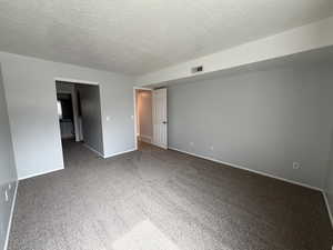 Empty room featuring carpet and a textured ceiling