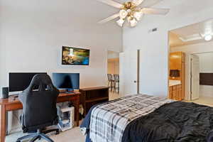 Bedroom with a desk, light carpet, vaulted ceiling, a ceiling fan, and connected bathroom