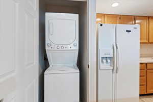 Laundry area with stacked washing machine and dryer and recessed lighting