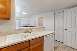 Kitchen featuring wood finish cabinets, light countertops, white dishwasher, and light tile patterned floors