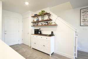 Interior space with light wood-type flooring, white cabinetry, wooden counters, and open shelves