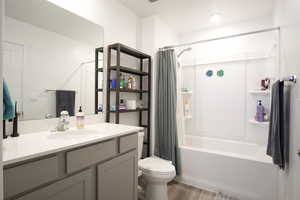 Full bath with vanity, shower / tub combo with curtain, and dark wood-style floors