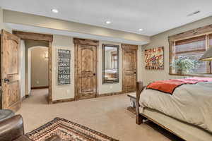 Bedroom with arched walkways, light colored carpet, recessed lighting, and a textured ceiling