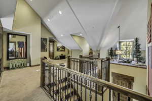 Hallway with carpet flooring and lofted ceiling