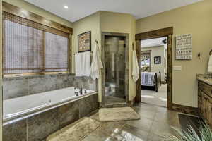 Ensuite bathroom with vanity, a stall shower, a jetted tub, light tile patterned floors, and ceiling fan