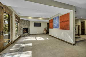 Unfurnished living room featuring light colored carpet and a stone fireplace