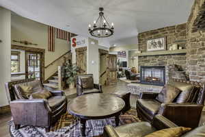Living area with a fireplace, wood finished floors, hanging lights, and a textured ceiling