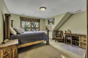 Bedroom with carpet, a textured ceiling, and a desk