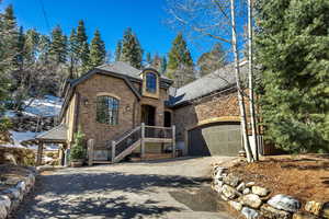 French country home featuring stone siding and asphalt driveway