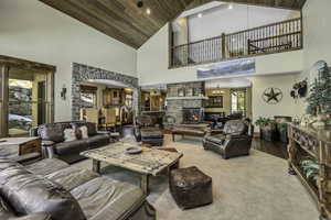 Carpeted living room with a warm lit fireplace, a vaulted wood ceiling, arched walkways, and wood finished floors