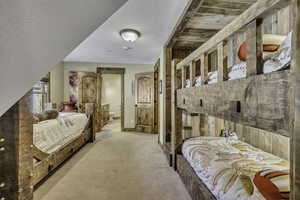 Bedroom with light carpet, connected bathroom, and a textured ceiling