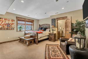 Bedroom featuring light carpet, recessed lighting, a textured ceiling, and ensuite bath