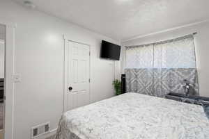 Bedroom with a textured ceiling and carpet flooring
