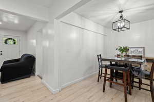 Dining room with a textured ceiling, light wood-type flooring, and hanging lights
