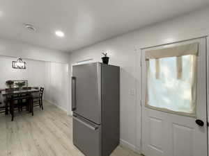 Kitchen with freestanding refrigerator, light wood finished floors, and recessed lighting