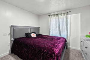 Carpeted bedroom featuring attic access and a textured ceiling