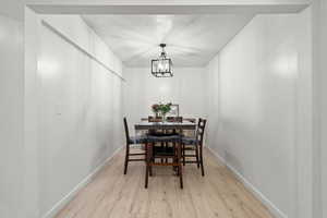 Dining space featuring light wood finished floors, a textured ceiling, and a chandelier
