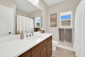 Bathroom with a shower with shower curtain, vanity, and light tile patterned floors