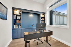Office area featuring light wood-type flooring and built in shelves