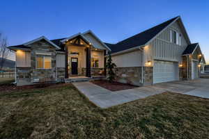 Modern inspired farmhouse with board and batten siding, stone siding, a front yard, and concrete driveway
