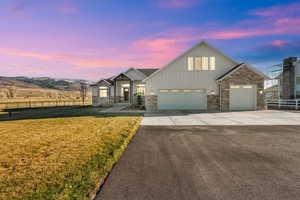 View of front of home featuring board and batten siding, driveway, stone siding, and a garage