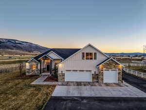 Modern inspired farmhouse featuring board and batten siding, stone siding, and concrete driveway