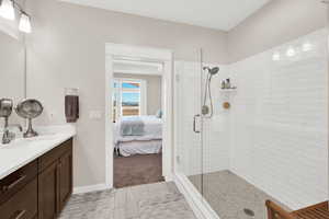 Ensuite bathroom with vanity, a shower stall, light tile patterned floors, and light colored carpet