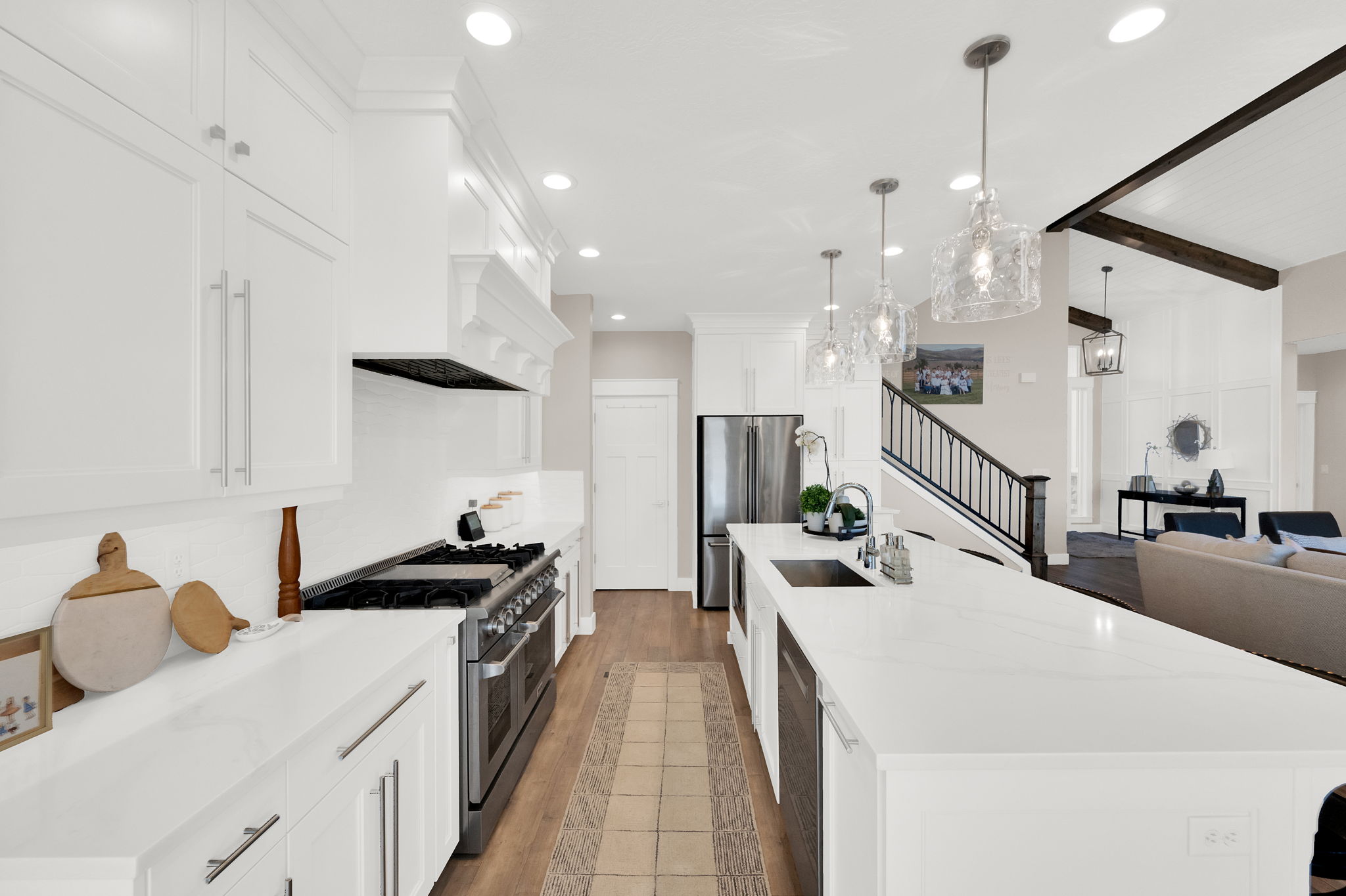 Kitchen featuring beam ceiling, light wood finished floors, stainless steel appliances, open floor plan, and a large island with sink