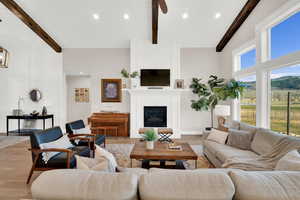 Living area with a glass covered fireplace, recessed lighting, wood finished floors, and vaulted ceiling with beams