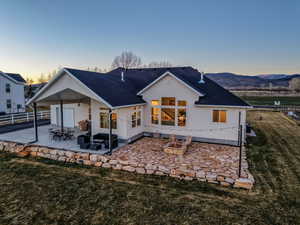 Back of house featuring a patio, a shingled roof, and stucco siding